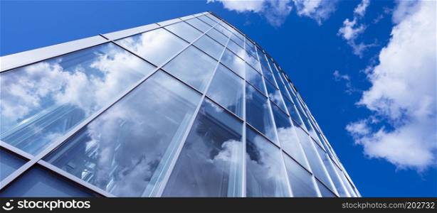 modern blue glass and metal office architecture facade reflects clouds and blue sky