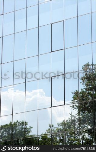 modern building glass reflects nature of trees and clouds
