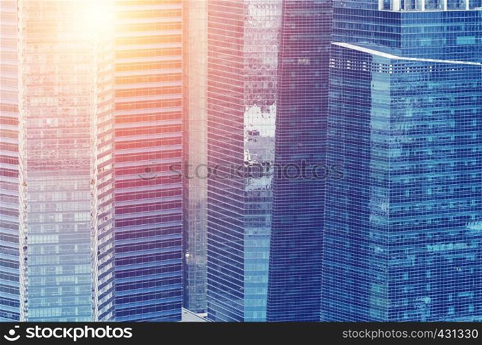 Modern building reflected on a blue glass wall windows with sunlight. Architecture and business background.