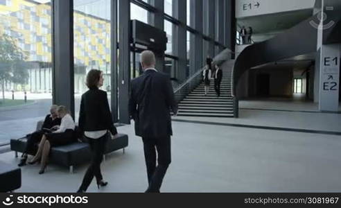 Modern business people walking in glass hall of office building