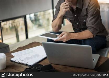 Modern businessman with tablet computer reading news and work report document at morning in cafe.