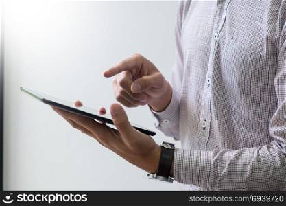 Modern businessman with tablet computer reading news and work report document at morning in office