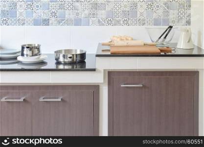 modern ceramic kitchenware and utensils on the black granite countertop