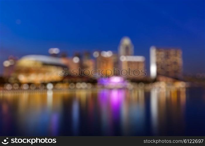 Modern city in the evening defocused blurred background - Singapore skyscrapers with reflection in water. Modern city defocused blurred background