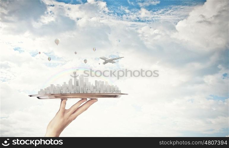 Modern city model. Hand holding metal tray with modern cityscape