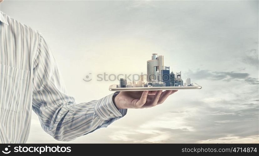 Modern city model. Hand holding tablet computer with cityscape on screen