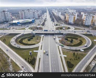 Modern city with the road in the form of a quatrefoil on the road junction of Odessa square around background of a cloudy sky autumn day. Aerial view from the drone. Kiev, Ukraine. Aerial view of the drone on the road junction of Odessa square with highway in the form of a quatrefoil with passing cars and a modern city against a cloudy sky. Kiev, Ukraine
