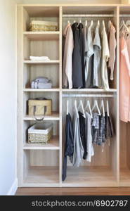 modern closet with row of cloths hanging in wooden wardrobe