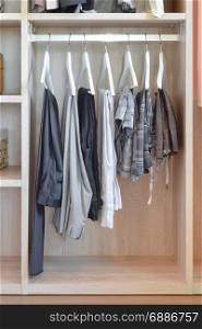 modern closet with row of pants hanging in wooden wardrobe