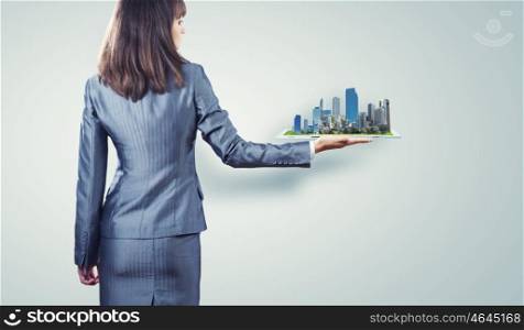 Modern construction. Back view of businesswoman holding in palm tablet pc with city image