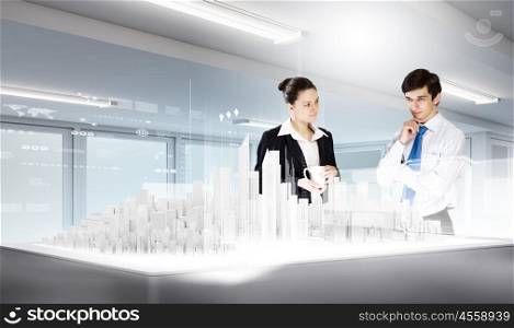 Modern construction. Two young businesspeople looking at construction project