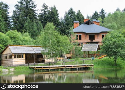 Modern cottage and a gazebo on shore of lake in Ukrainian Carpathians