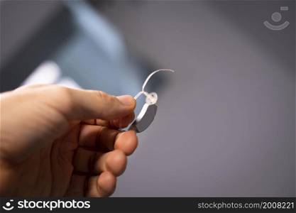Modern digital hearing aid in ear of middle aged 40s 50s man in hand