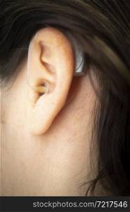 Modern digital hearing aid in ear of middle aged 40s woman