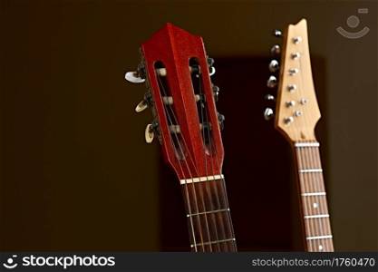 Modern electric and classical acoustic guitar fretboards closeup, brown background, nobody. String musical instrument, electro and live sound, music, equipment for musician. Electric and classical acoustic guitar fretboards
