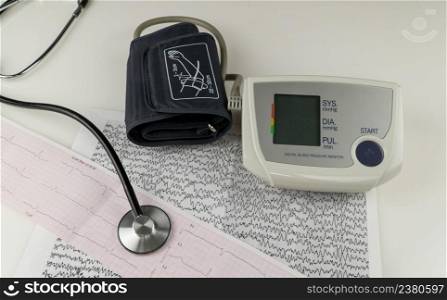 modern electric tonometer and a stethoscope on a cardiogram chart. household blood pressure monitor . blood pressure monitor with cardiogram