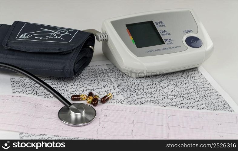 modern electric tonometer and a stethoscope on a cardiogram chart. household blood pressure monitor . blood pressure monitor with cardiogram