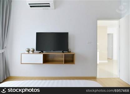 Modern Empty bedroom with led tv on white wall and wooden shelf