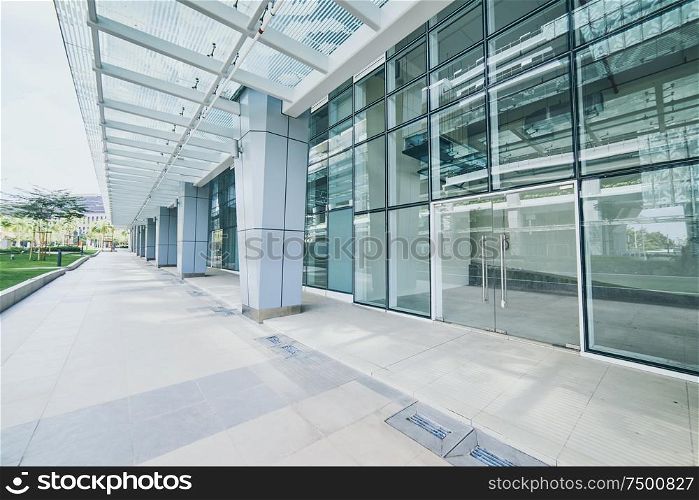 Modern empty office buildings with glass wall and empty pavement .