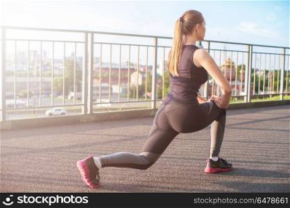 Modern fitness life. A woman in sportswear doing fitness exercises. City in sunny evening.