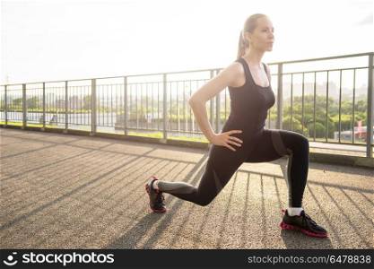 Modern fitness life. A woman in sportswear doing fitness exercises. City in sunny evening.