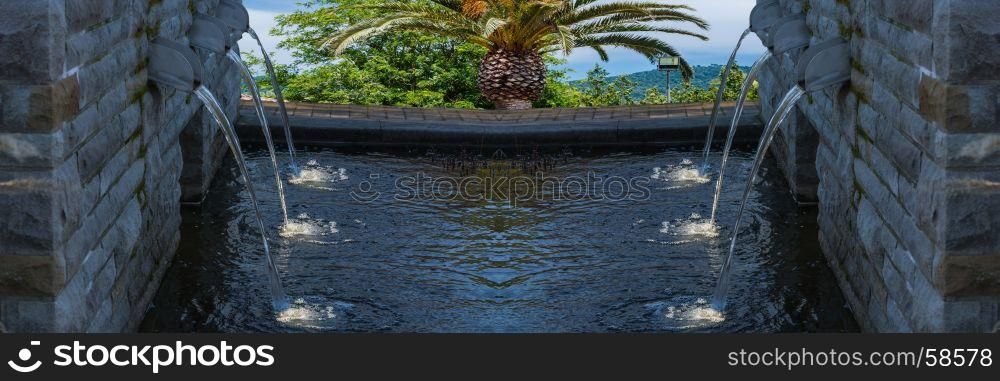 Modern fountain with six spotlighted water in the background sea and countryside.