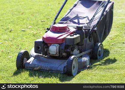 Modern gasoline lawn mower on a green meadow. Gardening equipment