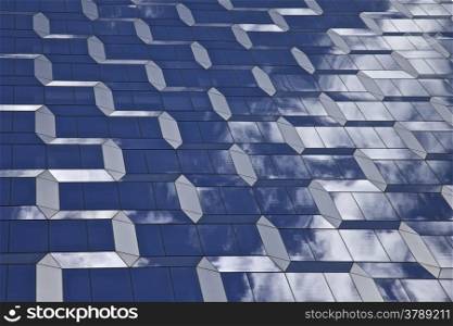 Modern glass Building with geometric shapes and reflecting the clouds