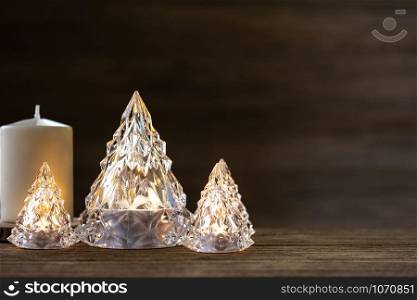 Modern glass Christmas tree with lights on dark wood table with wall for merry chirstmas and new year holiday greeting card backgrond. banner mock up with copy space for display product