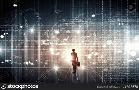Modern global technologies. Back view of businessman with suitcase in hands looking at virtual panel