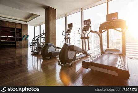 Modern gym room fitness center with set of treadmills staying in line , morning sunrise scene .