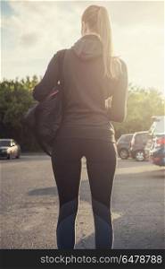Modern healthy lifestyle. A woman in sportswear ready for fitness exercises. City in sunny evening.