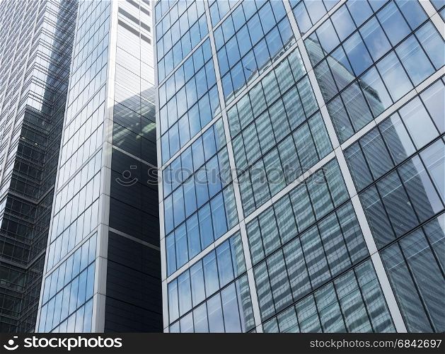 modern high rise corporate office buildings with reflections of blue sky and clouds