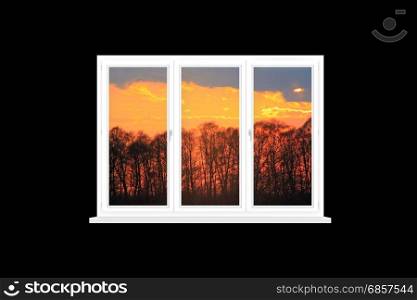 modern isolated window overlooking the scarlet sunset. view to beautiful scarlet sunset under dark trees from modern window isolated on the black
