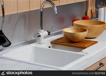 Modern kitchen interior with faucet and sink on foreground.