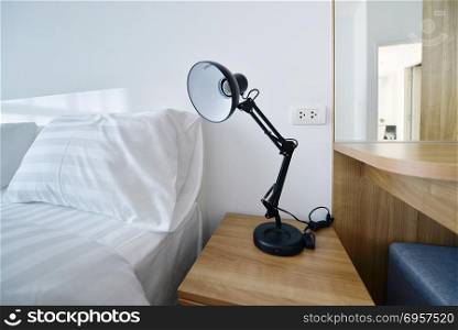 modern lamp on wooden nightstand in white modern bedroom, interi. modern lamp on wooden nightstand in white modern bedroom, interior design. modern lamp on wooden nightstand in white modern bedroom, interior design
