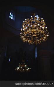 Modern lamps are like candles. gold-plated chandelier hangs in the old church near the icons. Modern lamps are like candles.. gold-plated chandelier hangs in the old church near the icons. Modern lamps are like candles.