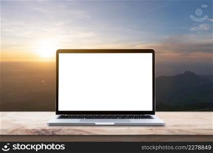 Modern Laptop computer with blank screen on wood table over mountain at sunrise sky background.