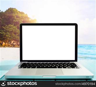 Modern laptop on blue wooden table with blank screen at tropical beach. working by the seaside