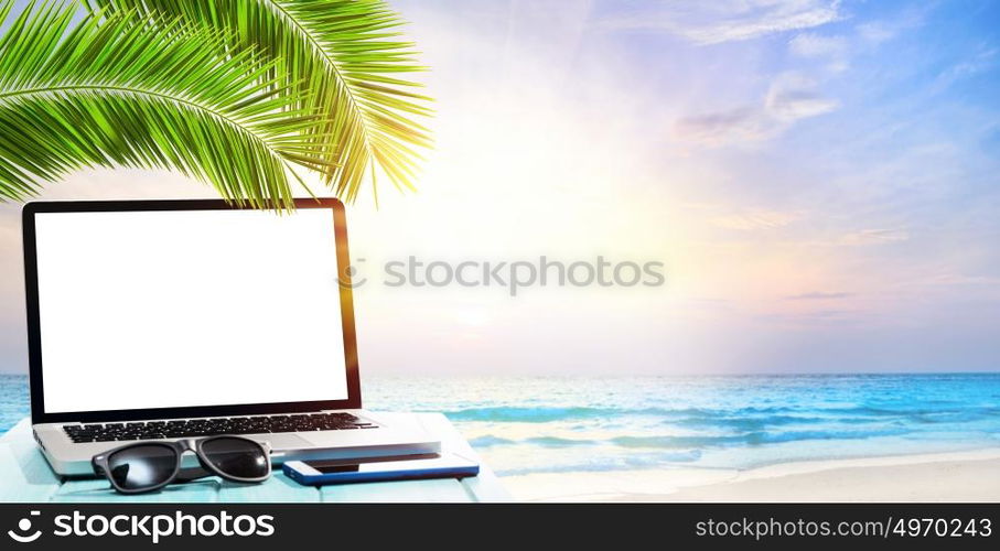 Modern laptop on blue wooden table with blank screen at tropical beach. working by the seaside