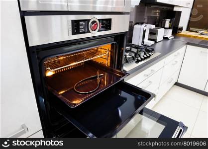 Modern luxury hi-tek black and white kitchen, clean interior design, focu at oven with open door