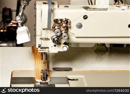 Modern machine for sewing furniture upholstery, the working part of the sewing machine close-up, copy space.. Industrial sewing machine for the manufacture of furniture upholstery.