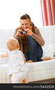 Modern mother making photos of baby at home&#xA;