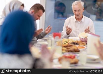 modern muslim family praying before having iftar dinner together during a ramadan feast at home