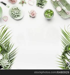 Modern natural skin care equipment with roses, succulents, facial mist water spray and green tropical leaves on white background, top view, flat lay, frame. Beauty concept