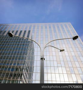 modern office architecture with glass and steel and lamp post under blue sky and clouds
