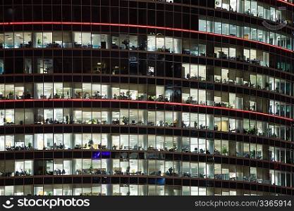modern office building with big windows at night, in windows light shines