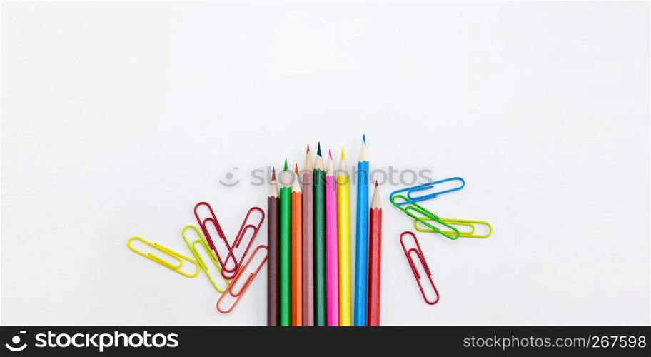 Modern office supplies concepts, Colored crayon pencils and clips on white background with wide banner, brochure, poster design template with copy space. Top view, Closeup.