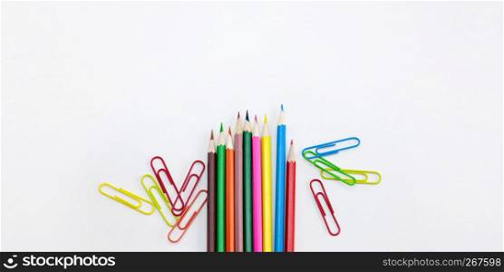 Modern office supplies concepts, Colored crayon pencils and clips on white background with wide banner, brochure, poster design template with copy space. Top view, Closeup.