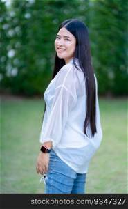 Modern portrait of beautiful happy Asian woman traveler wearing smartwatch wearing beautiful white dress and wear jeans lifestyle enjoying in the grass background